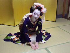Maiko bowing politely in a zashiki room.