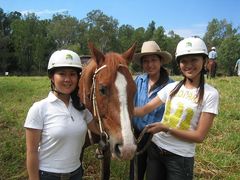 three women posing for a photo with brown horse