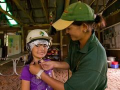 guide fastening helmet on a kid, horseback ride