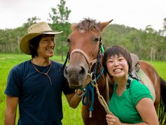 couple all smiles for a photo with brown horse