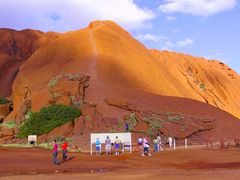 tourists reading signage at the base of ayers rock