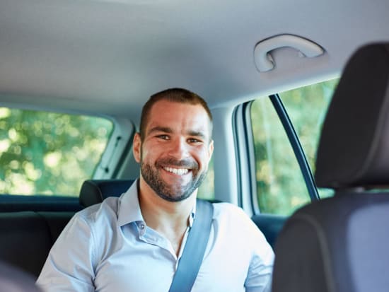 man with wide smile aboard a private car