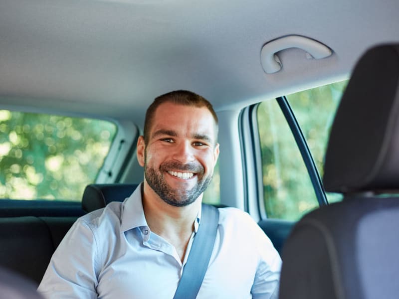man with wide smile aboard a private car