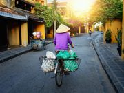 local wearing asian conical hat riding bicycle