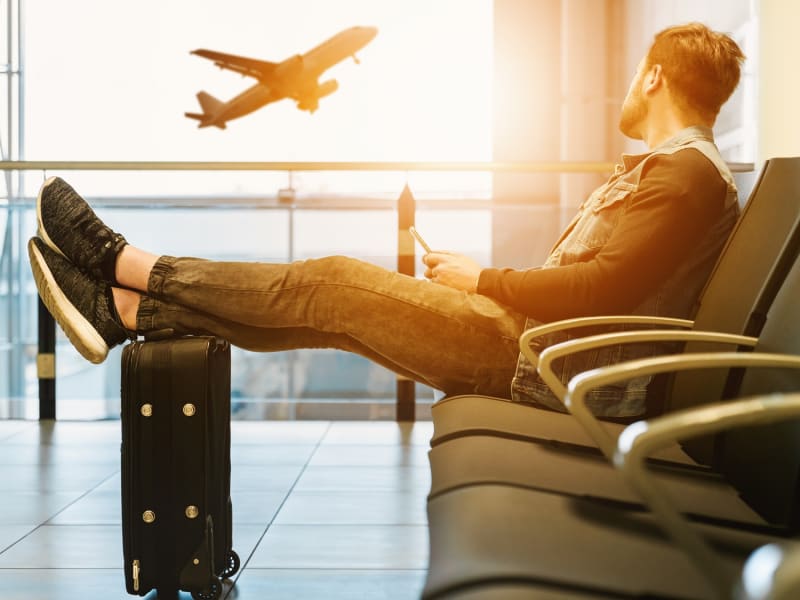man sitting with foot atop his suitcase airplane