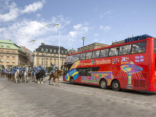 red city sightseeing bus passing knights on horses