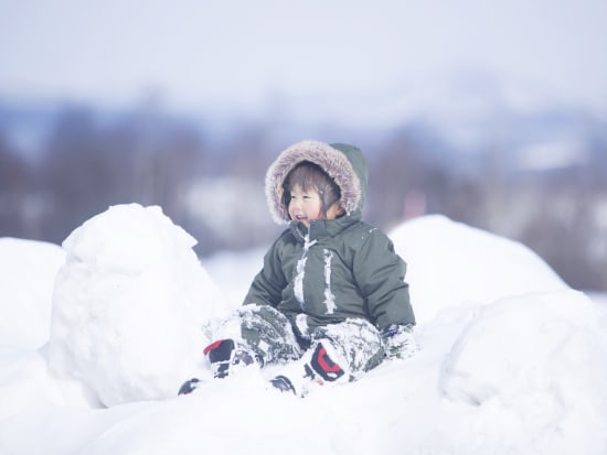 雪山に座る、3歳の男の子pixta_82559677_M