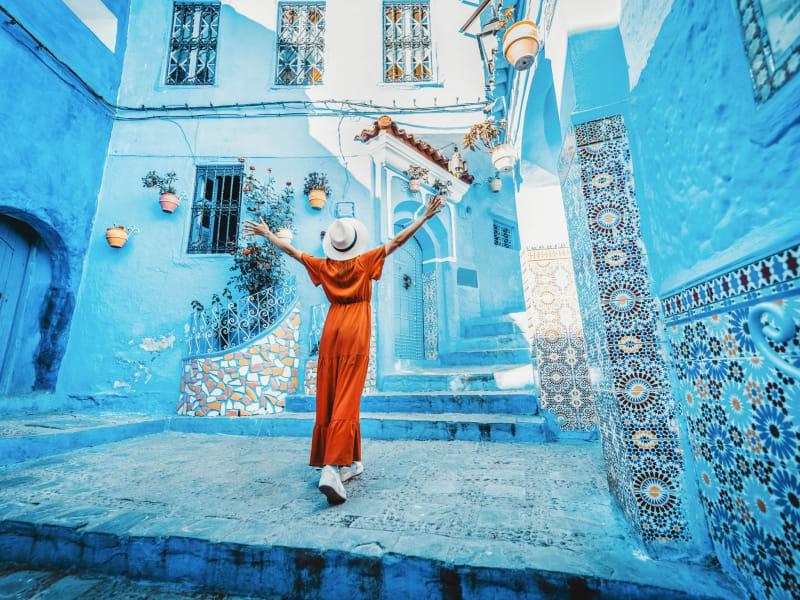 shutterstock_Chefchaouen_young-woman-red-dress-visiting-blue-2373574871