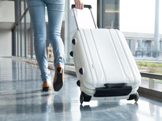 A woman walking with suit case_pixta_68137158_M