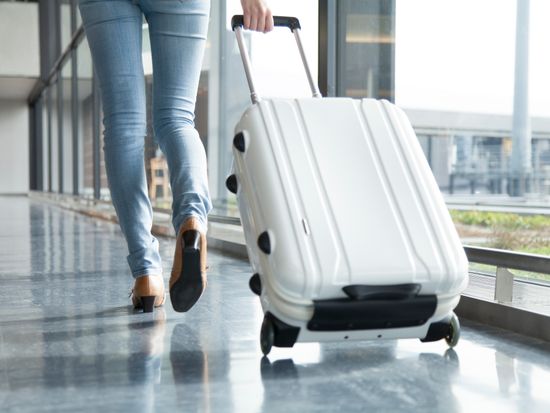 A woman walking with suit case_pixta_68137158_M