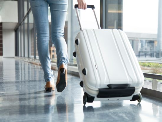 A woman walking with suit case_pixta_68137158_M